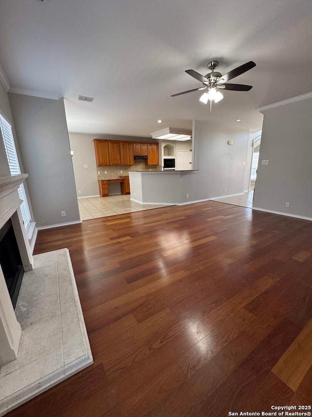 living room featuring ornamental molding, light wood finished floors, a fireplace, and baseboards