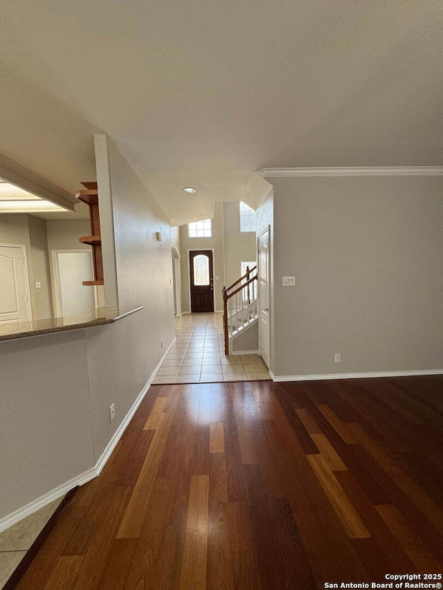 corridor featuring light wood-type flooring, baseboards, stairway, and ornamental molding