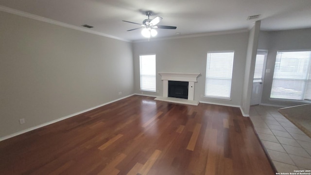 unfurnished living room featuring baseboards, visible vents, a fireplace with raised hearth, and ornamental molding