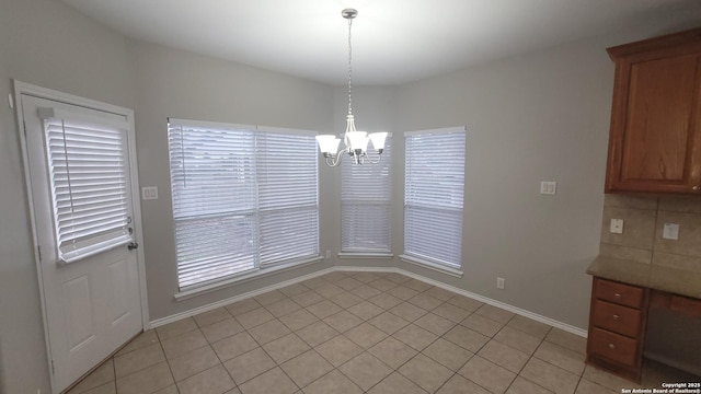 unfurnished dining area with a notable chandelier, baseboards, and light tile patterned floors