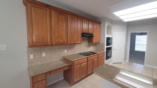 kitchen featuring black appliances, tasteful backsplash, brown cabinetry, and under cabinet range hood