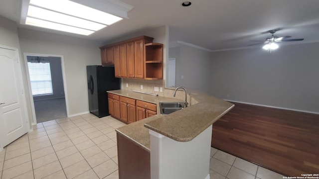 kitchen with a peninsula, brown cabinetry, open shelves, and a sink