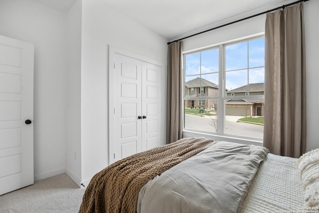 bedroom with baseboards, a closet, and light colored carpet