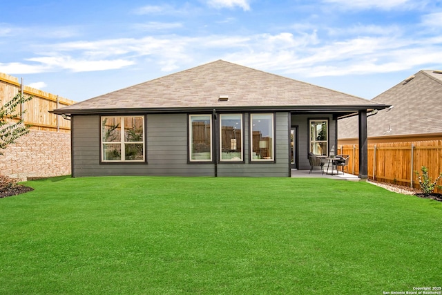 rear view of property with roof with shingles, a lawn, a patio, and a fenced backyard