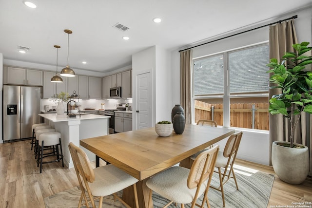 dining room with light wood finished floors, visible vents, and recessed lighting