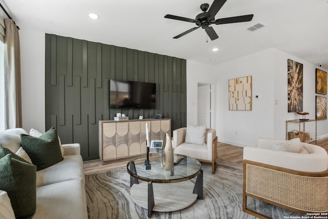 living room featuring ceiling fan, recessed lighting, an accent wall, wood finished floors, and visible vents