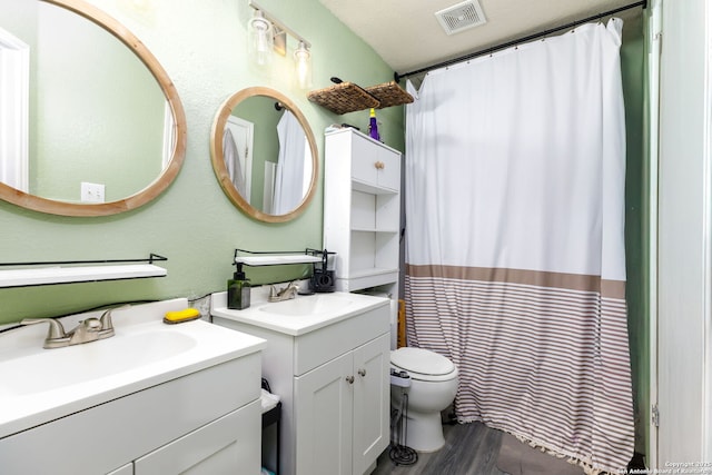 full bathroom featuring wood finished floors, two vanities, a sink, and visible vents