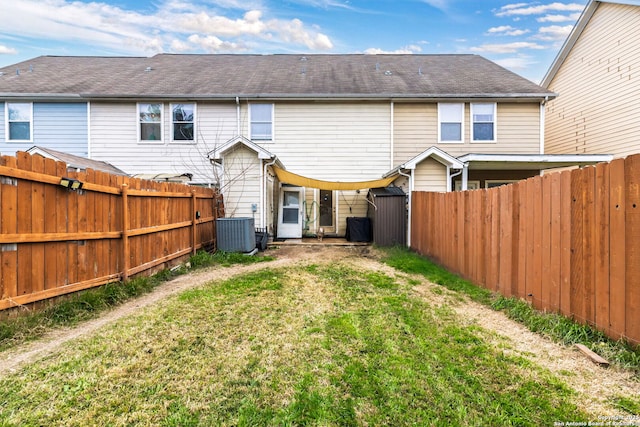 rear view of property with a yard, a fenced backyard, and central air condition unit