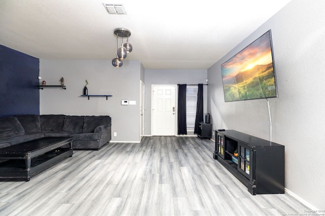 living area with light wood-style floors, baseboards, and visible vents