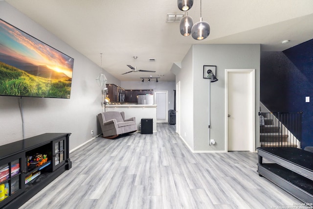 living room with visible vents, light wood-style flooring, baseboards, and stairs