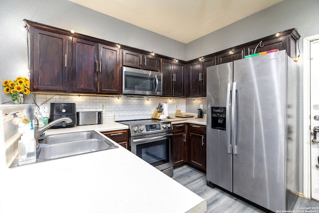 kitchen with light countertops, appliances with stainless steel finishes, backsplash, and a sink