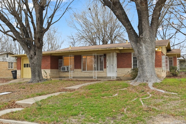 ranch-style house with brick siding, a front yard, a garage, cooling unit, and stone siding