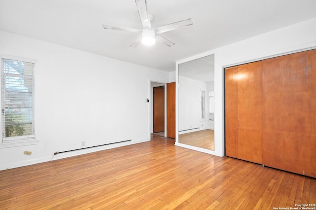 unfurnished bedroom with light wood-style floors, a baseboard radiator, a closet, and ceiling fan