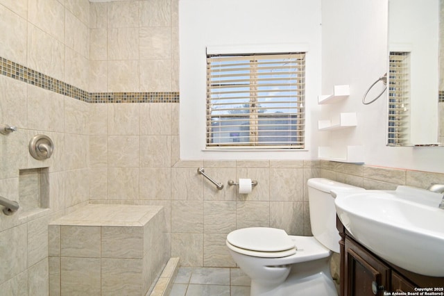 full bathroom featuring toilet, tile patterned flooring, a tile shower, vanity, and tile walls