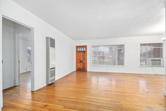 empty room with light wood-style floors, a heating unit, and baseboards