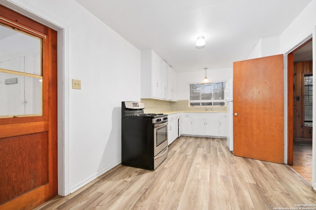 kitchen with white cabinets, light countertops, light wood finished floors, gas range, and pendant lighting