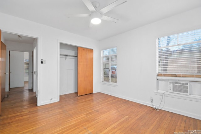 unfurnished bedroom with ceiling fan, cooling unit, wood finished floors, baseboards, and a closet