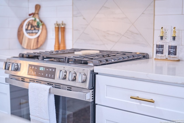 kitchen with stainless steel gas range, white cabinetry, and decorative backsplash