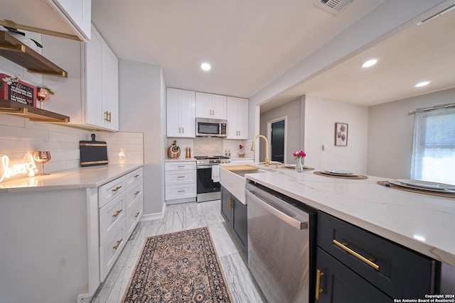 kitchen featuring white cabinetry, appliances with stainless steel finishes, open shelves, and dark cabinets