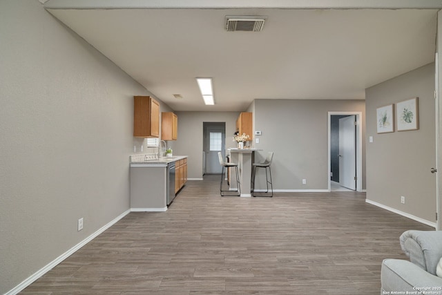 kitchen with visible vents, dishwasher, a breakfast bar, open floor plan, and light countertops