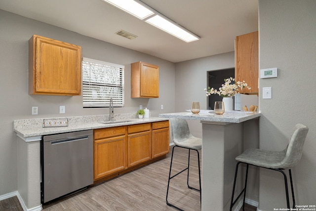 kitchen featuring visible vents, dishwasher, a breakfast bar area, a peninsula, and light wood-type flooring