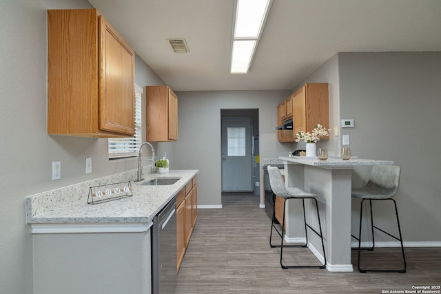 kitchen with visible vents, a sink, light stone countertops, dishwasher, and a kitchen bar