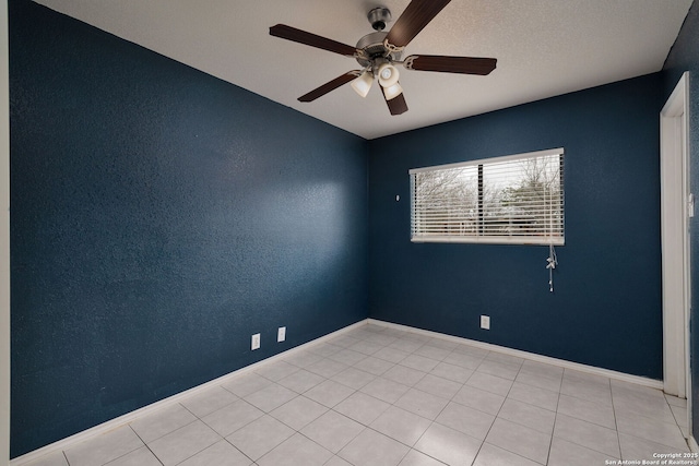 empty room with a textured wall, ceiling fan, baseboards, and light tile patterned floors