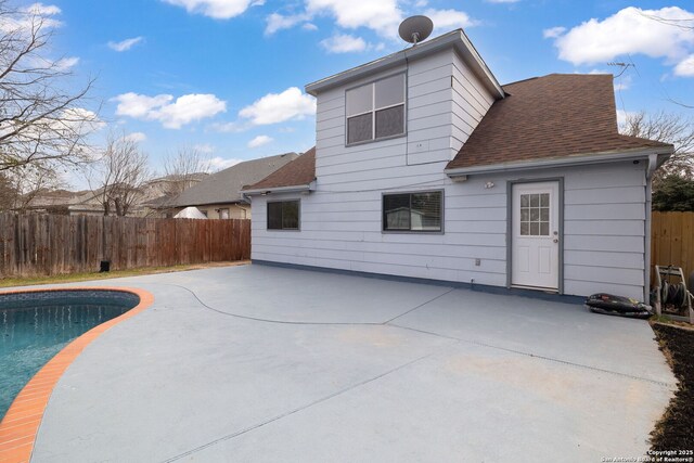 rear view of property with a fenced in pool, roof with shingles, a patio, and fence