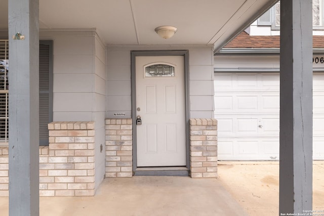 doorway to property with a garage and roof with shingles