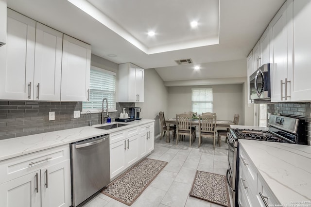 kitchen featuring stainless steel appliances, white cabinets, visible vents, and a sink