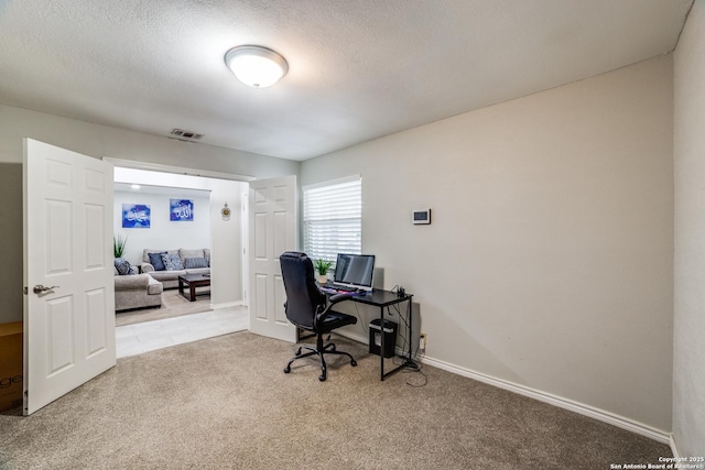 office area with baseboards, visible vents, a textured ceiling, and light colored carpet