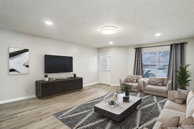 living area with recessed lighting, baseboards, a textured ceiling, and light wood finished floors