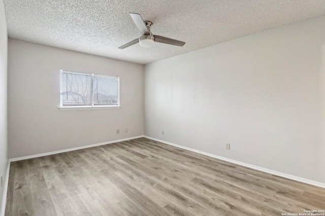 spare room featuring light wood-type flooring, ceiling fan, a textured ceiling, and baseboards