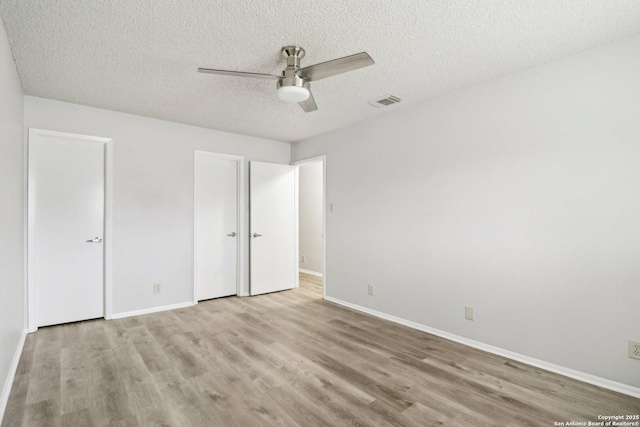 unfurnished bedroom with a textured ceiling, ceiling fan, visible vents, baseboards, and light wood finished floors