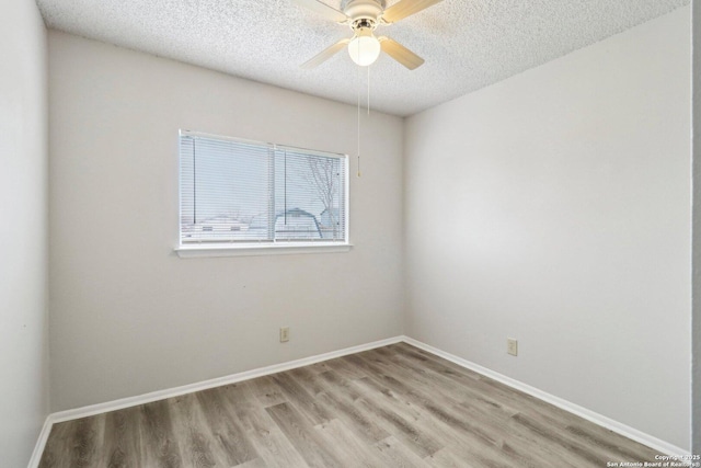 spare room with a ceiling fan, light wood-style flooring, baseboards, and a textured ceiling