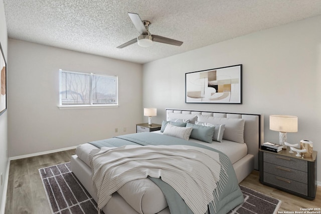 bedroom featuring ceiling fan, a textured ceiling, baseboards, and wood finished floors