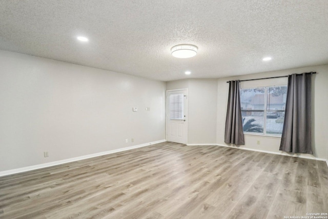 spare room featuring light wood-style floors, baseboards, a textured ceiling, and recessed lighting