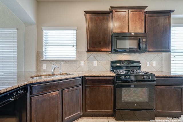 kitchen featuring black appliances, plenty of natural light, a sink, and light stone countertops