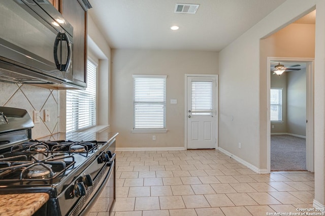 kitchen with light tile patterned floors, visible vents, decorative backsplash, black appliances, and baseboards