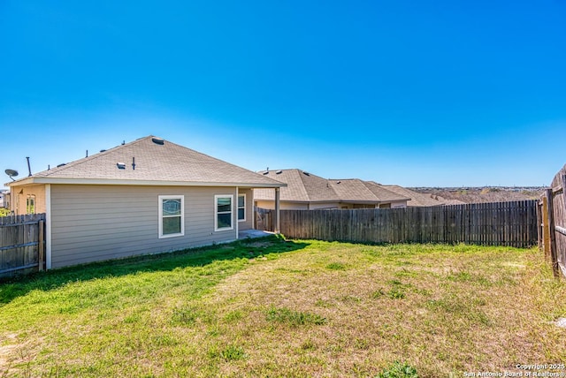 rear view of house featuring a lawn and a fenced backyard