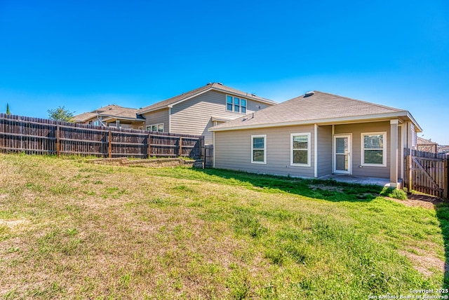 rear view of house with a fenced backyard and a lawn