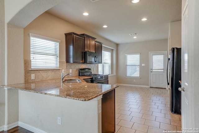 kitchen featuring black appliances, a peninsula, visible vents, and light stone countertops