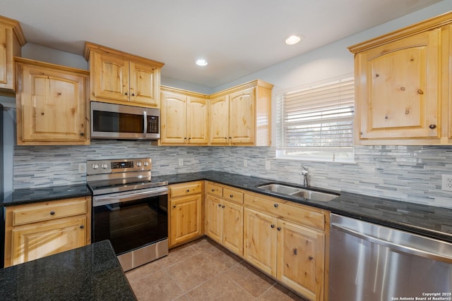 kitchen featuring light tile patterned floors, a sink, appliances with stainless steel finishes, decorative backsplash, and light brown cabinetry