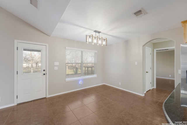 interior space featuring arched walkways, dark tile patterned floors, visible vents, and a healthy amount of sunlight