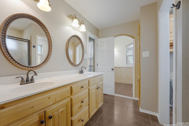 bathroom with tile patterned flooring, a shower with shower door, a sink, and double vanity