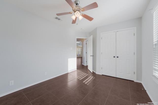 unfurnished bedroom with visible vents, baseboards, a closet, and dark tile patterned flooring