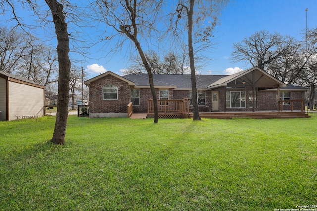 rear view of house with a yard, brick siding, and a wooden deck