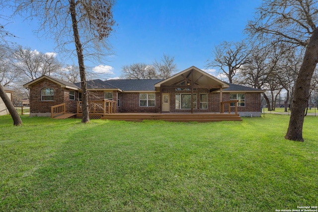 rear view of property with a deck, brick siding, and a lawn