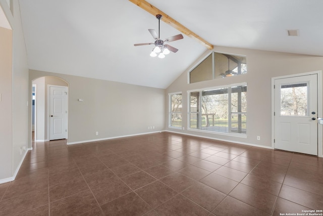 unfurnished living room with arched walkways, beamed ceiling, dark tile patterned floors, and baseboards