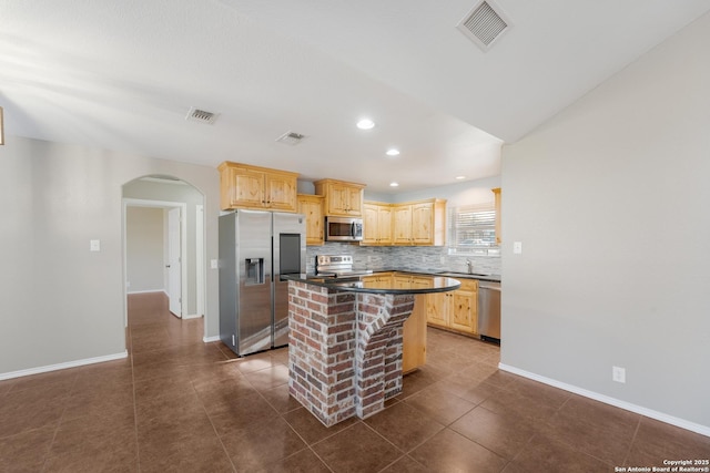 kitchen with stainless steel appliances, dark countertops, visible vents, and a center island